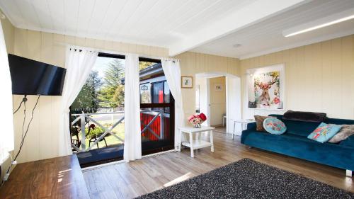 a living room with a blue couch and a large window at Tullys Hut - Walk To Hikes & Waterfalls in Wentworth Falls
