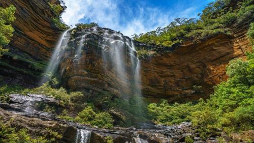 a waterfall on the side of a rocky cliff at Tullys Hut - Walk To Hikes & Waterfalls in Wentworth Falls