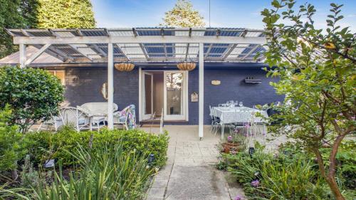 Casa azul con patio con mesa y sillas en Atalanta Wentworth Falls, en Wentworth Falls