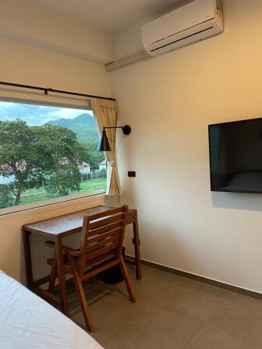 Habitación con mesa, TV y silla. en Parkside Pai, en Pai
