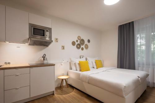 a white bedroom with a bed and a kitchen at Pytloun Apartments Zelený Háj in Liberec