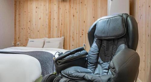 a black chair sitting next to a bed at Luxury Motel Daejeon in Daejeon