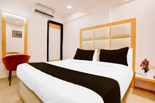 a bedroom with a large white bed and a red chair at Super Collection O Andheri West Near KokilaBen Hospital in Mumbai