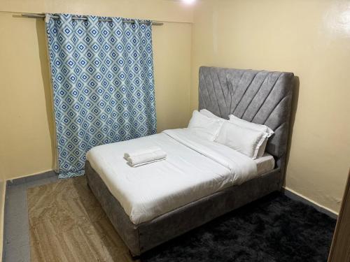a bed in a small room with a blue curtain at Luxury-Inn Apartment in Nyeri