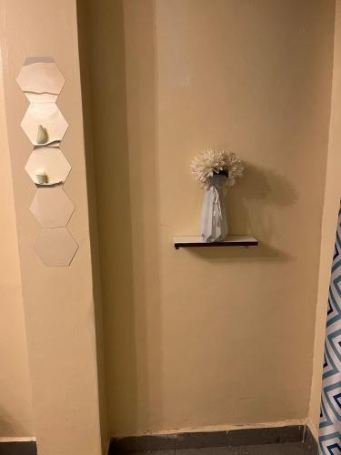 a room with a shelf with a vase of flowers at Luxury-Inn Apartment in Nyeri
