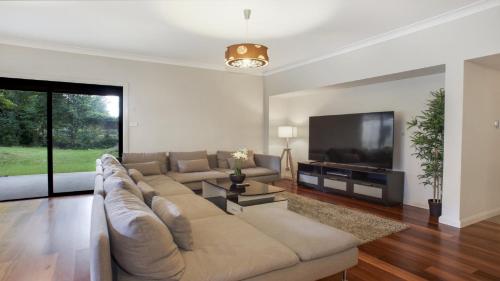 a living room with a large couch and a flat screen tv at The Cherry Blossom Blackheath in Blackheath