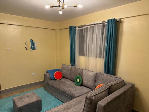 a living room with a brown couch and a window at Luxury-Inn Apartment in Nyeri
