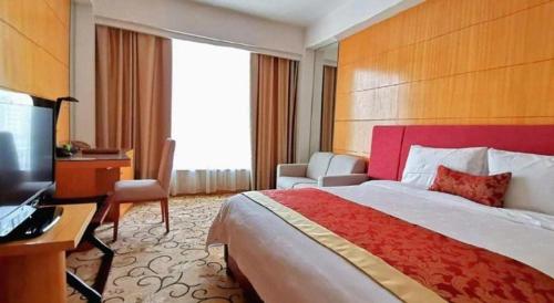 a hotel room with a bed and a desk and a television at Golden Lustre Hotel in Shenzhen