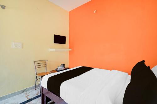 a bedroom with an orange wall with a bed and a chair at Super Hotel O Ramachandrapuram formerly known Nataraja Boarding & Lodging in Bengaluru