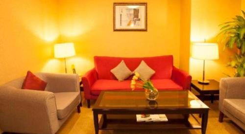 a living room with a red couch and a coffee table at Changchun Zhuozhan Days Hotel in Changchun