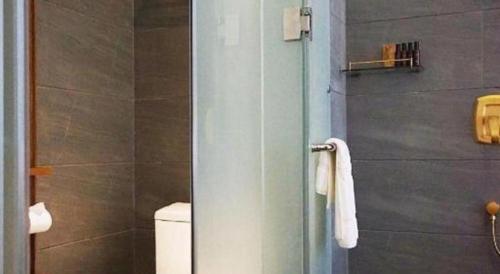 a bathroom with a toilet and a glass door at James Joyce Coffetel Beijing Yizhuang Rongjing East Street Subway Station in Beijing