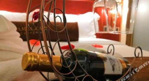 a bottle of wine on a table next to a bed at James Joyce Coffetel Beijing Yizhuang Rongjing East Street Subway Station in Beijing