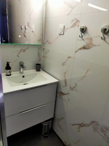 une salle de bain blanche avec un lavabo et un miroir dans l'établissement T2 au calme résidence avec piscine - Les Hauts de Balaruc, à Balaruc-les-Bains