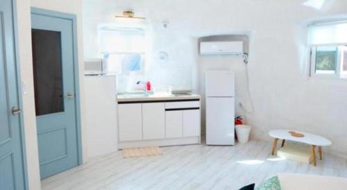 a white kitchen with a refrigerator and a table at All That Water Pension in Gapyeong