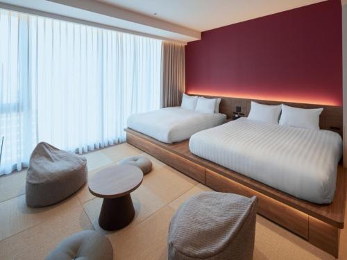 a hotel room with two beds and a table at FAV LUX Sapporo Susukino in Sapporo