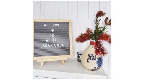 a black and white sign and a vase with a plant at White Jacaranda Tiny House by Tiny Away in Maleny