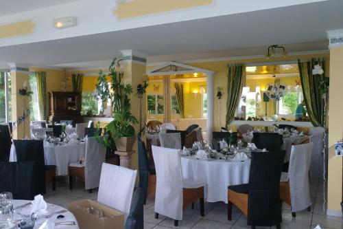 uma sala de jantar com mesas e cadeiras brancas em Hostellerie Saint Clément em Vic-sur-Cère