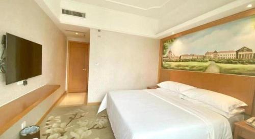 a bedroom with a white bed and a painting on the wall at Out Sky Hotel in Huizhou