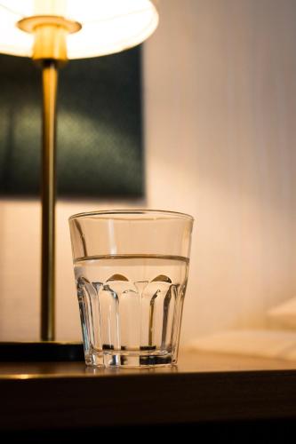 a glass sitting on a table next to a lamp at Villa ENTO HotelWestEnd in Frankfurt/Main