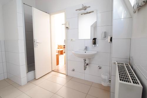 a white bathroom with a sink and a mirror at Villa ENTO HotelWestEnd in Frankfurt/Main