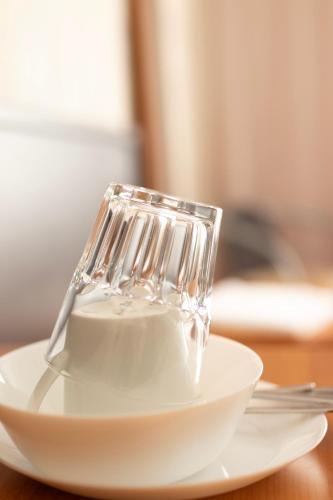 a glass sitting on top of a white plate at Villa ENTO HotelWestEnd in Frankfurt/Main