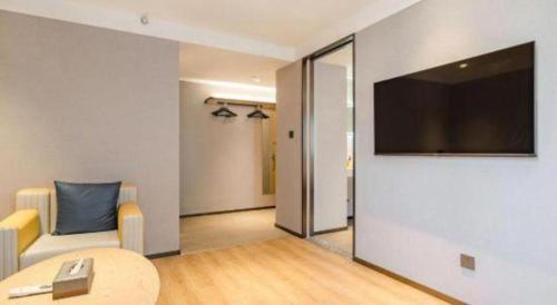 a living room with a couch and a television on a wall at Jinjiang Inn Qingdao Development Zone Jinggangshan Rd. in Huangdao