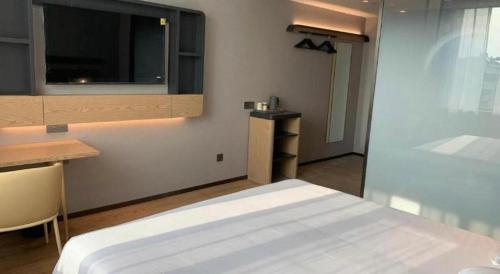 a bedroom with a bed and a tv on the wall at Jinjiang Inn Qingdao Development Zone Jinggangshan Rd. in Huangdao