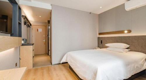 a bedroom with a large white bed and a hallway at Jinjiang Inn Qingdao Development Zone Jinggangshan Rd. in Huangdao