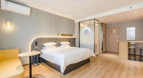 a bedroom with a large white bed and a table at Jinjiang Inn Qingdao Development Zone Jinggangshan Rd. in Huangdao