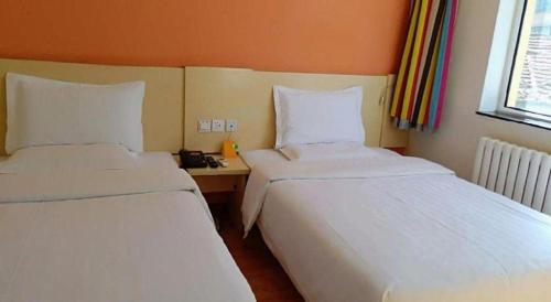 two beds sitting next to each other in a room at 7 Days Inn Hohhot Hailiang Xinhua Square Metro Station in Hohhot