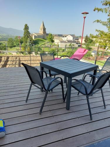 une table de pique-nique et deux chaises sur une terrasse dans l'établissement Maison de vacances à la montagne avec vue panoramique, à Bolquère-Pyrénées 2000