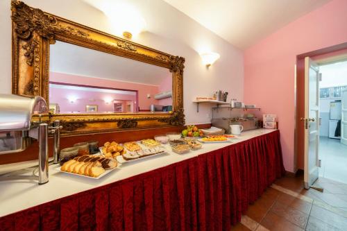 a table with a buffet of food in front of a mirror at Hotel Raffaello Prague in Prague