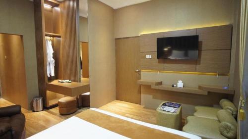 a living room with a couch and a tv at Hotel Pondok Asri Boyolali in Mojosongo