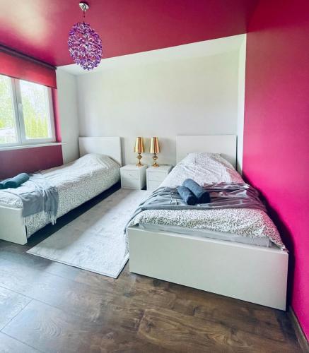 a bedroom with two beds and a pink wall at Cozy Family House with Sauna & Garden in Kärdla