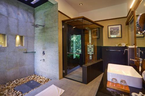 a bathroom with a shower and a sink and a tub at Reen Resorts Aanavilasam Plantation Thekkady in Thekkady