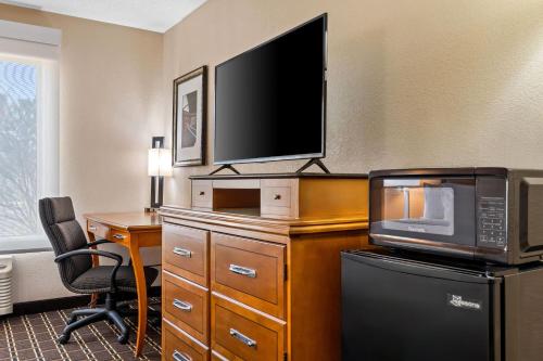 a room with a desk with a microwave and a television at Days Inn by Wyndham Black River Falls - Access to ATV Trail in Black River Falls