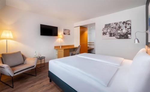 a hotel room with a bed and a chair at Wyndham Garden Potsdam in Potsdam