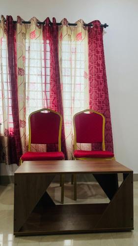 two chairs sitting on a table in front of curtains at Elite Residency in Vāniyambalam
