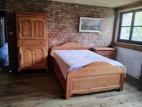 - une chambre avec un lit en bois et un mur en briques dans l'établissement Gite du putting-golf, à Saint-Sylvestre-Cappel