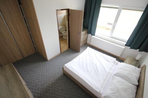 a small bedroom with a bed and a window at Penzión Aurora Patince in Patince