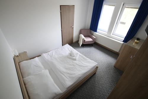 a bedroom with a white bed and a chair at Penzión Aurora Patince in Patince
