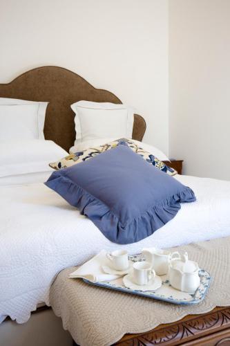 a tray with cups and saucers on a bed at Palazzo Cacace Relais in Meta