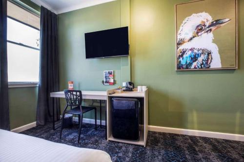 a hotel room with a desk and a painting of a bird at Nightcap at Pritchards Hotel in Mount Pritchard