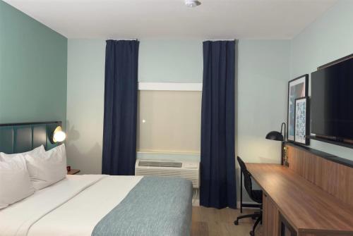a bedroom with a bed and a desk and a television at Wingate by Wyndham Farmington NM in Farmington