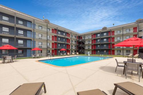 a pool with tables and chairs in front of a building at Ramada by Wyndham Kenner New Orleans Airport South in Kenner