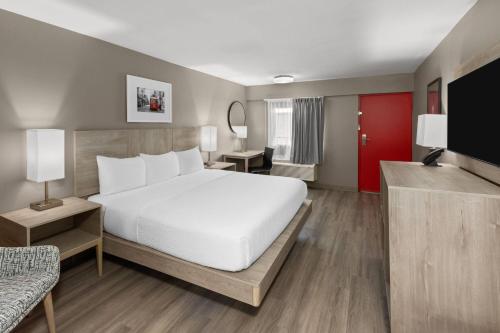 a bedroom with a white bed and a red door at Ramada by Wyndham Kenner New Orleans Airport South in Kenner