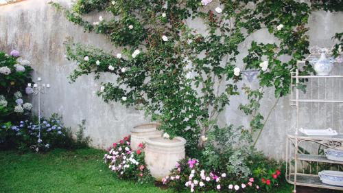 a garden with flowers in pots and a wall at Palazzo Cacace Relais in Meta