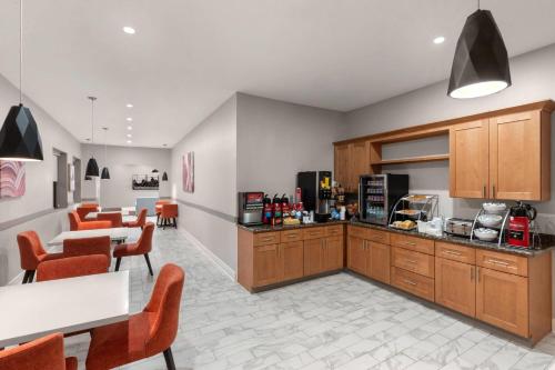 a kitchen with wooden cabinets and a table and chairs at Ramada by Wyndham Kenner New Orleans Airport South in Kenner