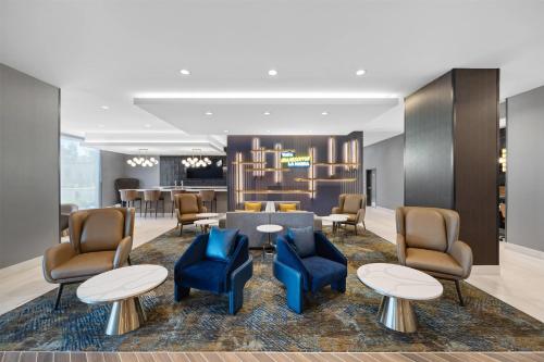 a lobby with blue chairs and tables and a kitchen at La Quinta Inn & Suites by Wyndham La Habra in La Habra