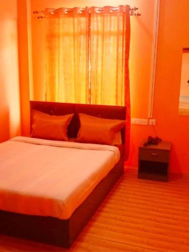 - une chambre avec un lit aux murs orange et une fenêtre dans l'établissement Perfect View Homestay, à Cherrapunji